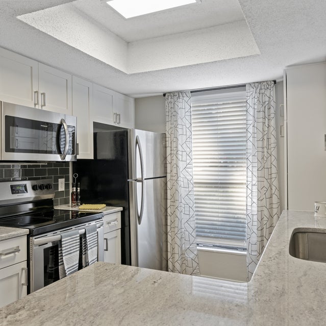 Andover At Crabtree Apartments - Kitchen With Stainless Steel Appliances, White Cabinetry And Dark Gray Subway Tile
