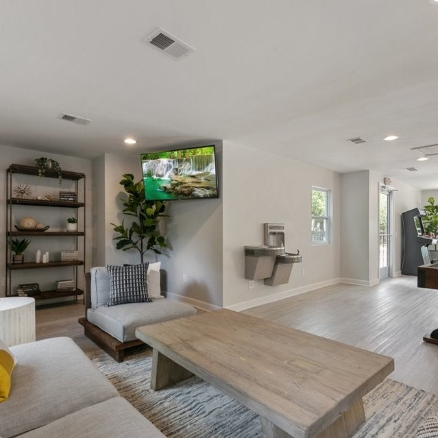 Andover at Crabtree Apartments - clubhouse with comfortable sofas and shuffleboard table