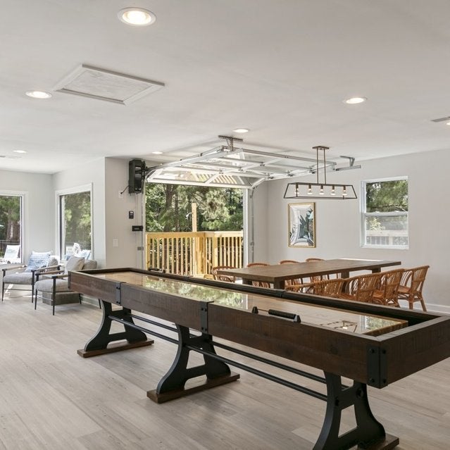 Andover at Crabtree Apartments - clubhouse with shuffleboard and dining table overlooking pool