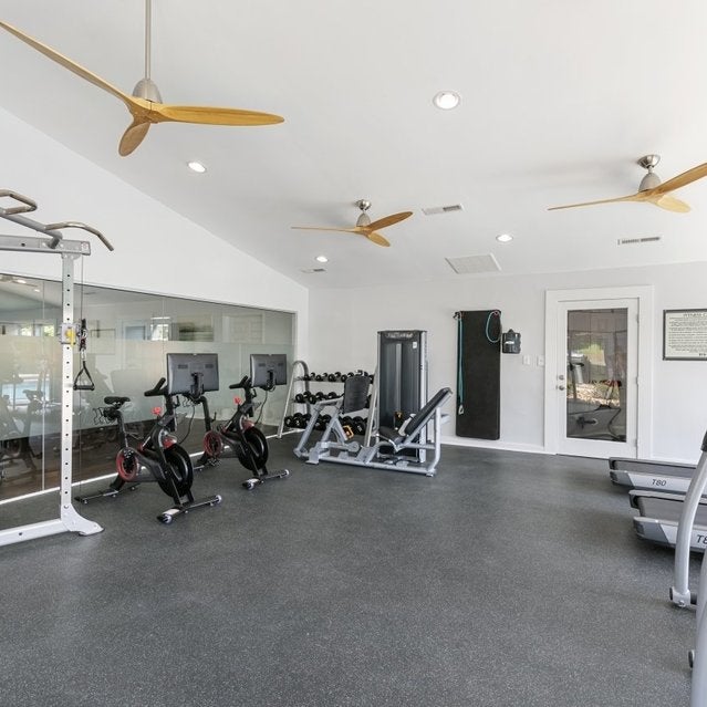 Andover at Crabtree Apartments - fitness center with cardio equipment, Peloton bikes, free weights, and weight lifting machines