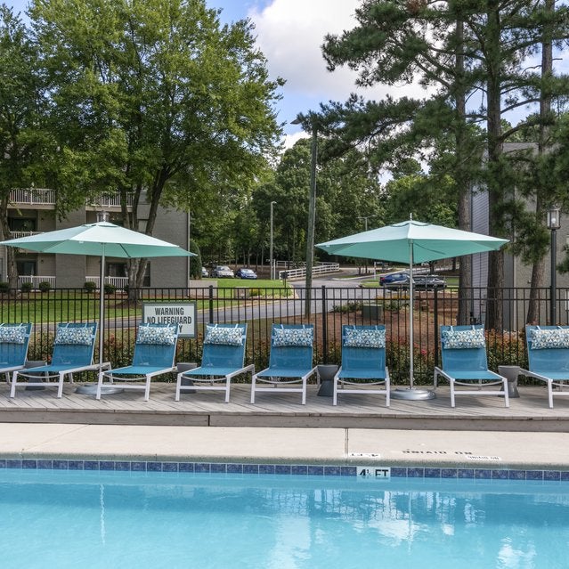 Andover at Crabtree Apartments - pool surrounded by trees and lounge seating